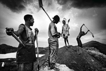 Labourers shovelling hillocks of extracted coal